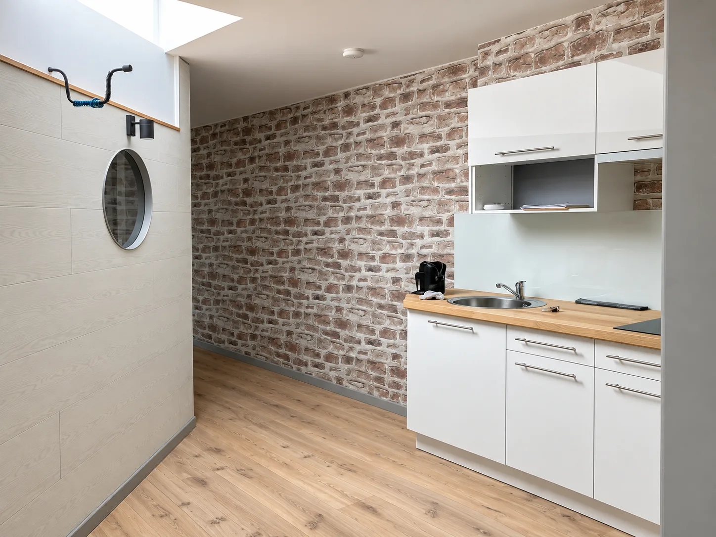 Cuisine blanche avec plan de travail en bois devant un mur de briques