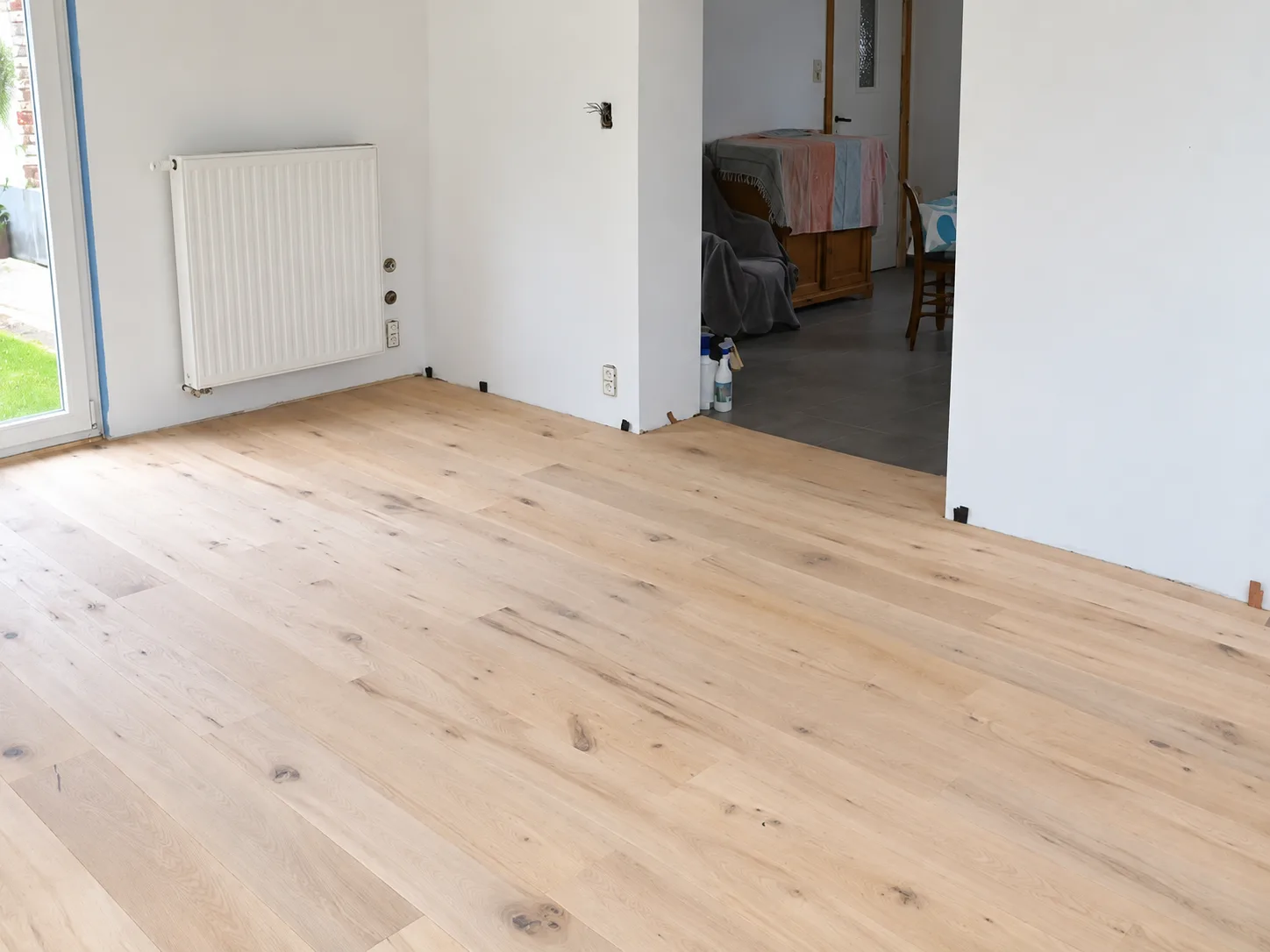 Parquet en chêne clair posé dans une pièce, près d’un radiateur blanc