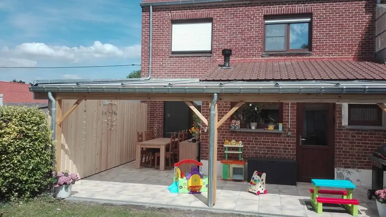 Terrasse couverte par une structure en bois devant une maison en briques