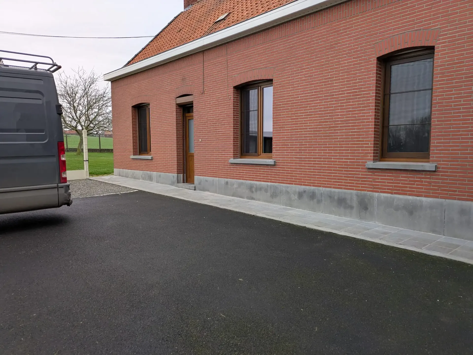 Façade en briques rouges avec fenêtres cintrées et porte d’entrée en bois