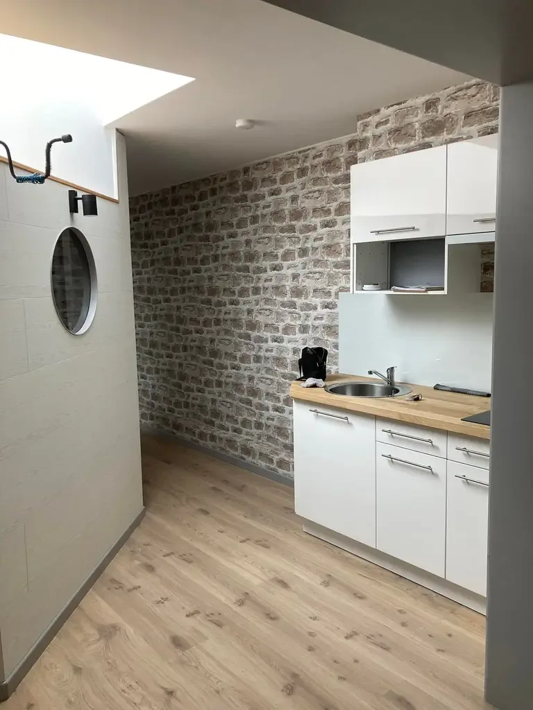 Cuisine blanche avec plan de travail en chêne devant un mur en briques