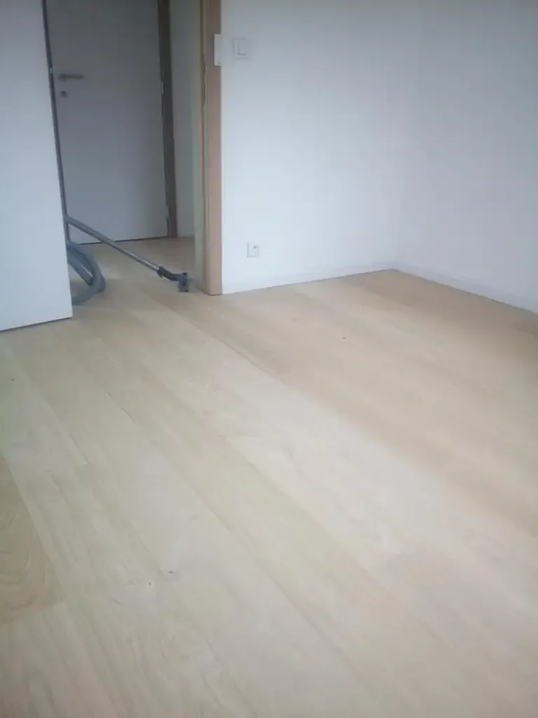 Parquet clair à larges lames dans une pièce aux murs blancs